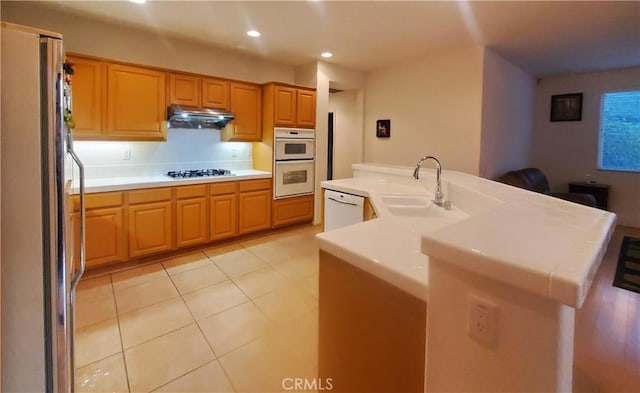 kitchen with sink, light tile patterned flooring, white appliances, and a kitchen island with sink