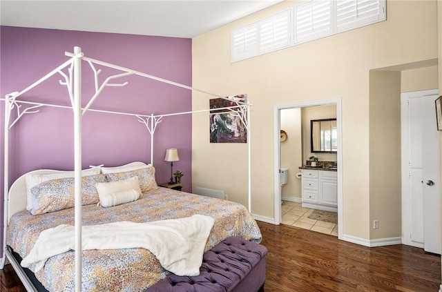 bedroom with dark hardwood / wood-style flooring, connected bathroom, and vaulted ceiling