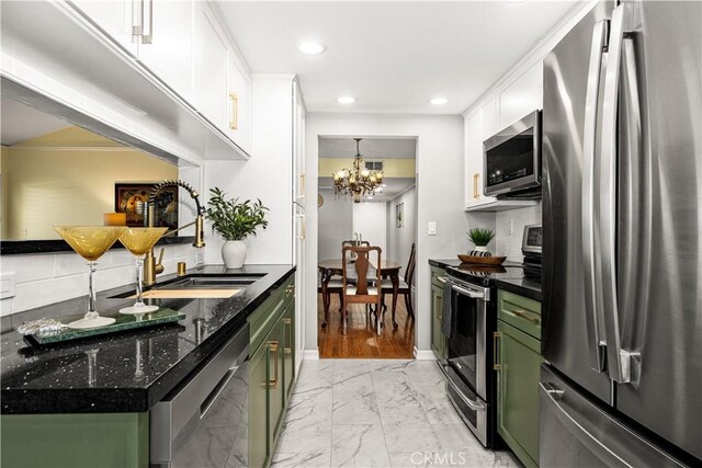 kitchen with appliances with stainless steel finishes, green cabinets, decorative backsplash, white cabinets, and sink