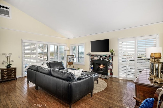 living room featuring a fireplace, dark wood-type flooring, vaulted ceiling, and a healthy amount of sunlight