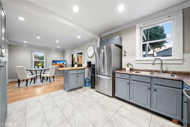 kitchen with stainless steel fridge, gray cabinets, tasteful backsplash, crown molding, and sink