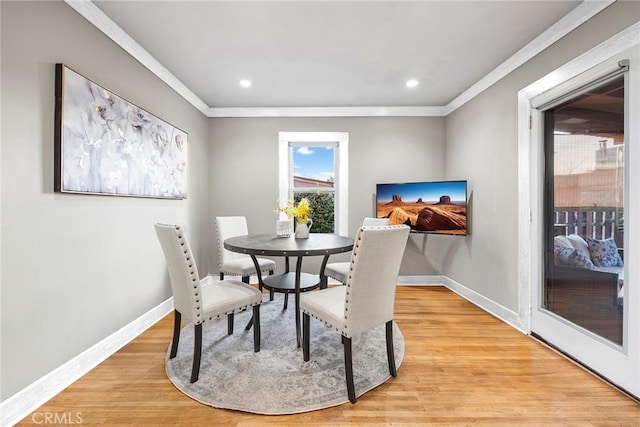 dining area with ornamental molding and light hardwood / wood-style floors