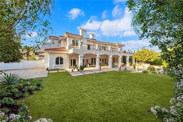 back of house featuring a lawn, a patio area, and a balcony