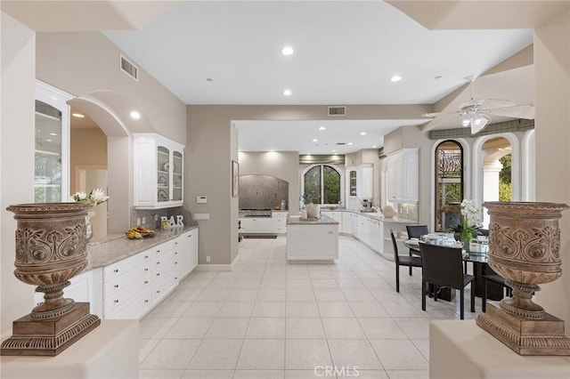 kitchen with light tile patterned flooring, ceiling fan, a kitchen island, and white cabinets