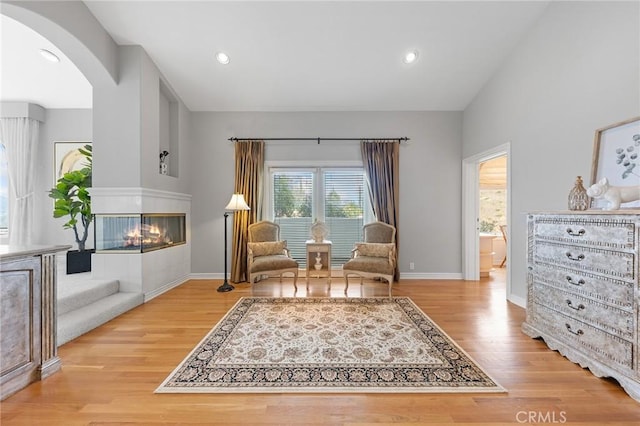 sitting room featuring a multi sided fireplace and light hardwood / wood-style flooring