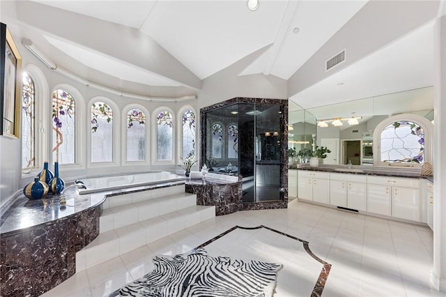 bathroom with vanity, tile patterned flooring, vaulted ceiling, and a relaxing tiled tub