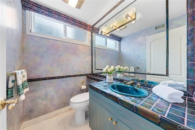 bathroom with toilet, vanity, and tile patterned flooring