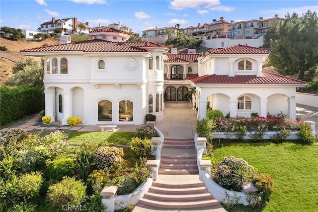 back of property featuring a lawn, french doors, and a balcony