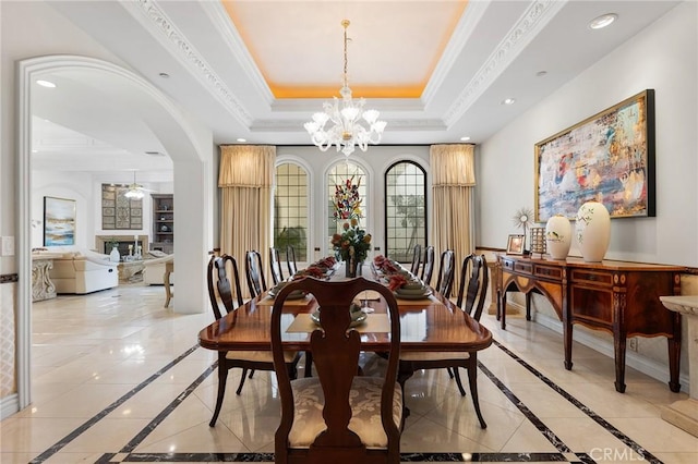 dining area with crown molding, a raised ceiling, and an inviting chandelier