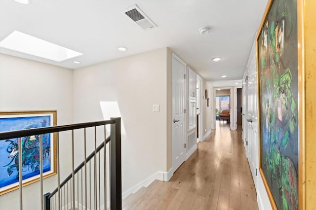 hallway with a skylight and light wood-type flooring