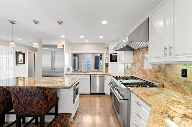 kitchen featuring high end appliances, extractor fan, light stone countertops, white cabinets, and decorative light fixtures