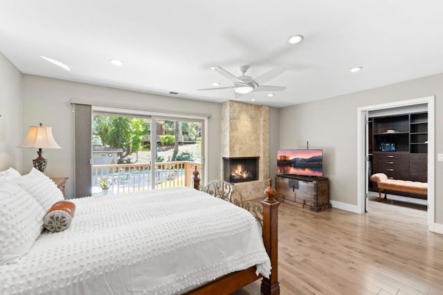 bedroom with access to outside, a fireplace, ceiling fan, and light hardwood / wood-style flooring