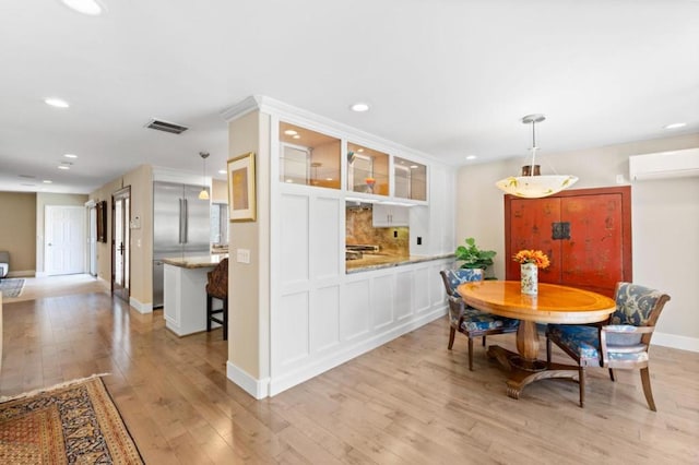 dining room featuring a wall unit AC and light hardwood / wood-style floors