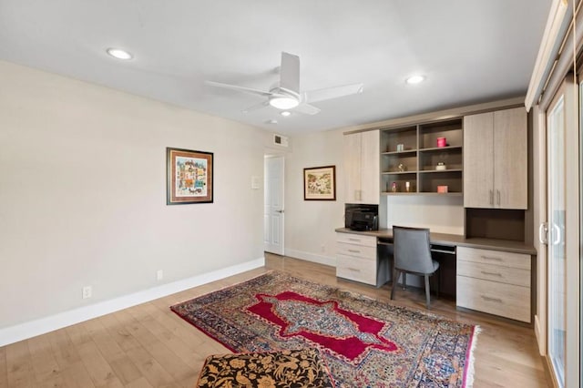 home office with ceiling fan, built in desk, and light wood-type flooring