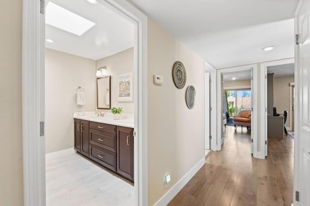 hallway with sink and light hardwood / wood-style floors