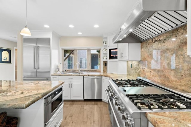 kitchen featuring sink, hanging light fixtures, range hood, high end appliances, and white cabinets