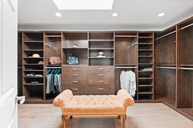 walk in closet with a skylight and light hardwood / wood-style floors