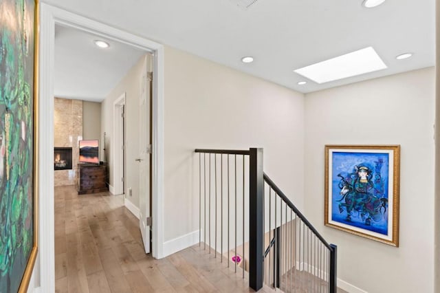 hallway with light hardwood / wood-style flooring and a skylight