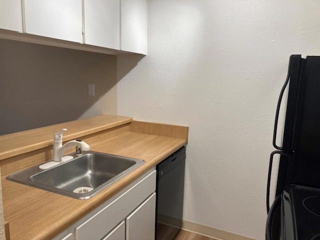 kitchen with sink, black appliances, and white cabinets