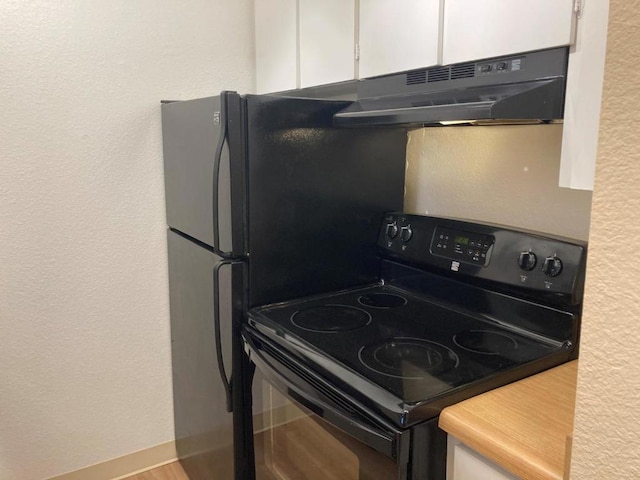 kitchen featuring black range with electric stovetop and white cabinets