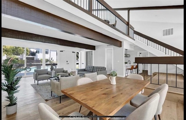 dining room featuring beamed ceiling and light wood-type flooring