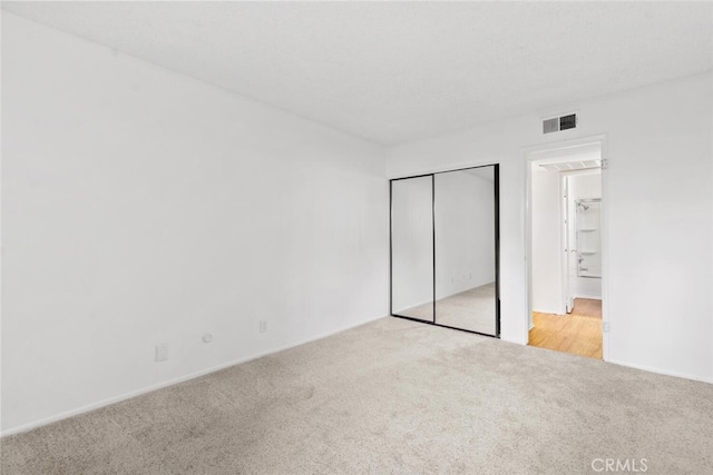 unfurnished bedroom featuring light colored carpet and a closet