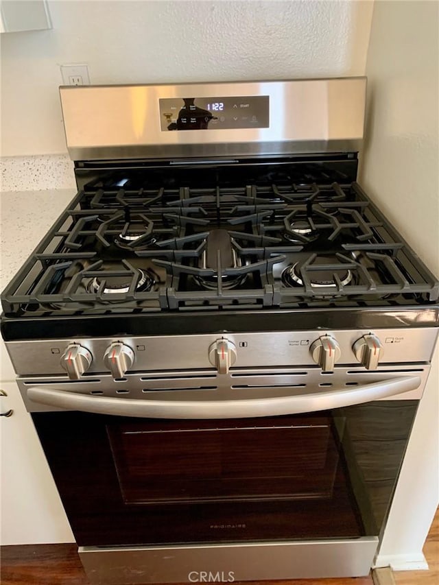 interior details featuring hardwood / wood-style flooring and stainless steel gas range oven