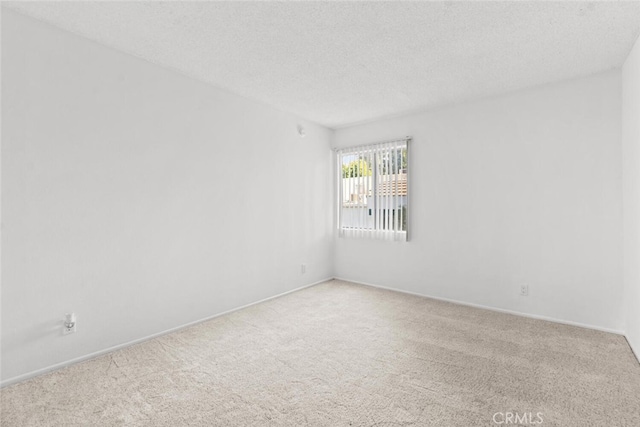 unfurnished room featuring light colored carpet and a textured ceiling