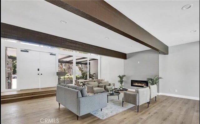 living room with a fireplace, beam ceiling, and light hardwood / wood-style floors