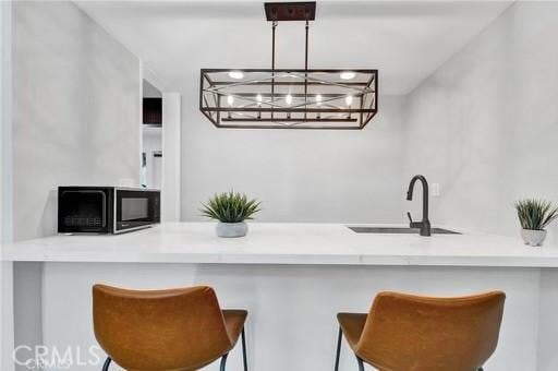 kitchen featuring sink, hanging light fixtures, a breakfast bar, and kitchen peninsula