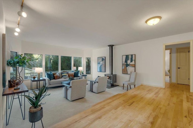 living room with rail lighting, a wood stove, and light hardwood / wood-style flooring