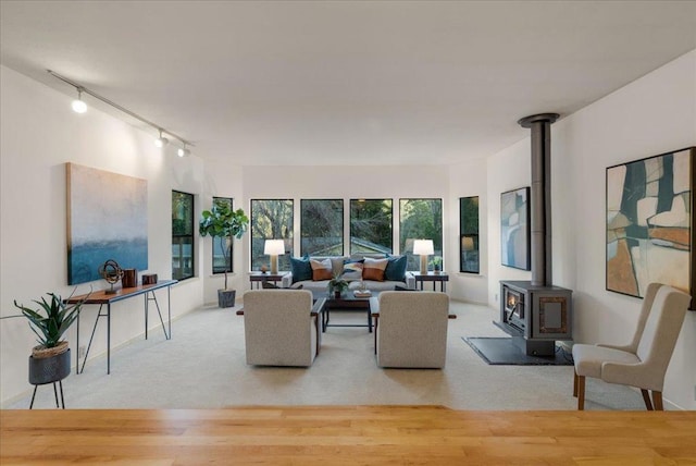 living room featuring a wood stove, light colored carpet, and track lighting