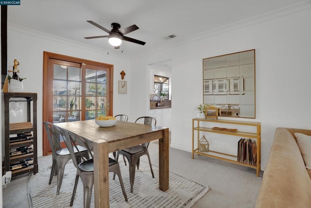 dining area featuring ceiling fan, light colored carpet, and ornamental molding