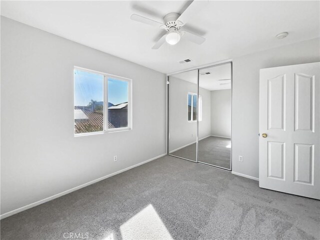 unfurnished bedroom with ceiling fan, carpet floors, and a closet