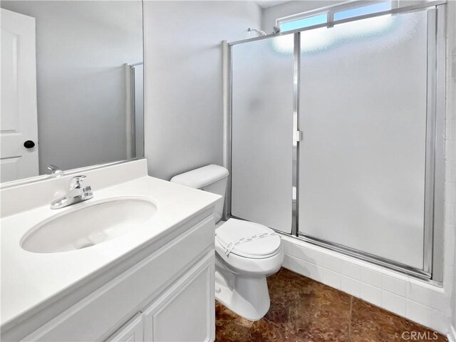 bathroom with a shower with door, vanity, and toilet