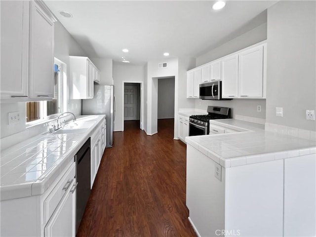 kitchen with stainless steel appliances, sink, white cabinets, and kitchen peninsula