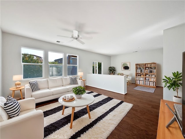 living room featuring dark wood-type flooring and ceiling fan