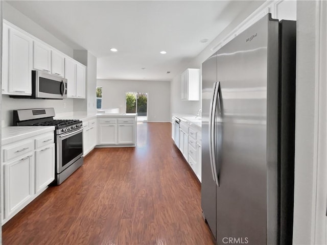 kitchen featuring sink, appliances with stainless steel finishes, white cabinetry, dark hardwood / wood-style flooring, and kitchen peninsula