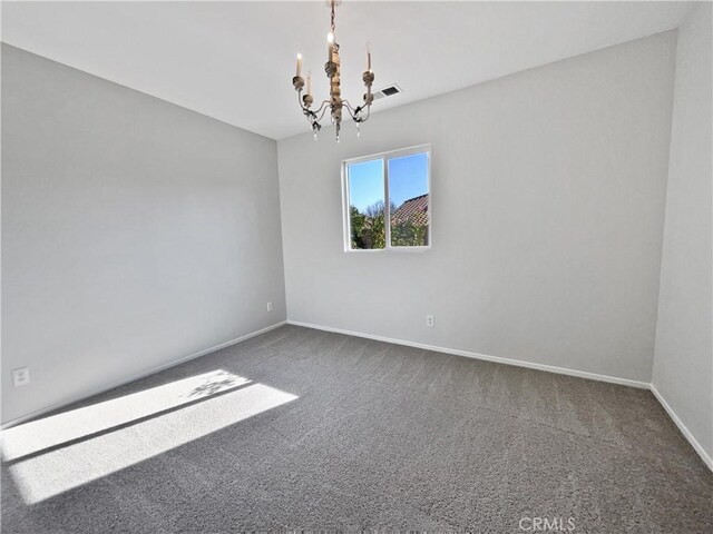 carpeted empty room with an inviting chandelier