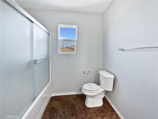 bathroom featuring enclosed tub / shower combo and toilet