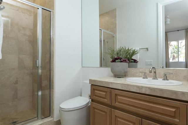 bathroom with vanity, a shower with door, and toilet