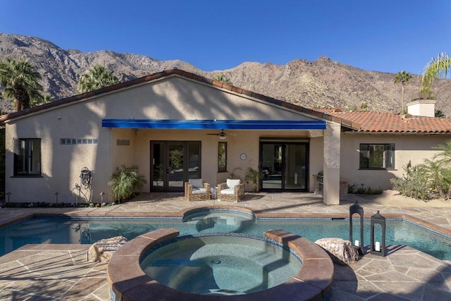 back of house featuring a mountain view, a patio, ceiling fan, and an in ground hot tub