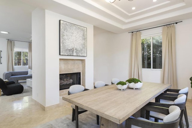 dining room featuring a high end fireplace and a raised ceiling