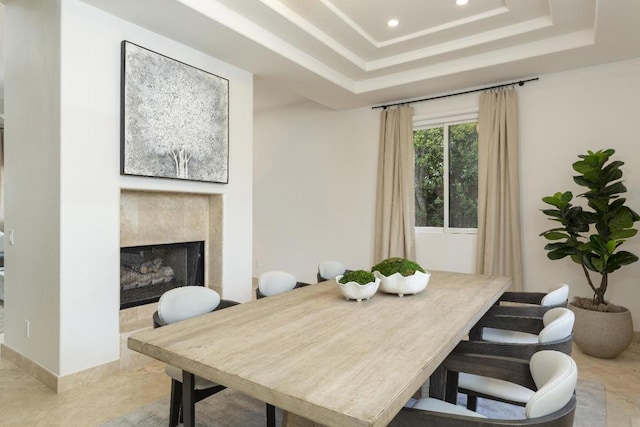 dining space with a high end fireplace and a raised ceiling