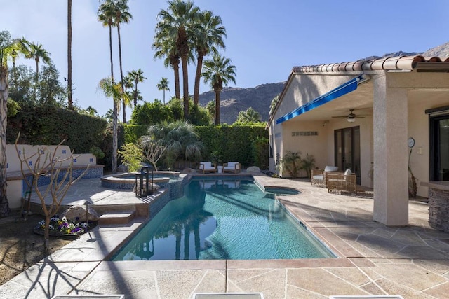 view of pool featuring an in ground hot tub, ceiling fan, a mountain view, and a patio area