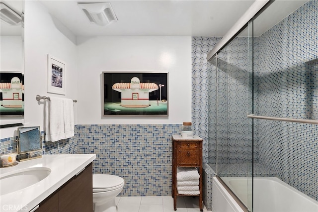 full bathroom with toilet, tile walls, vanity, enclosed tub / shower combo, and tile patterned flooring