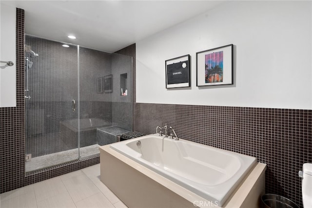 bathroom featuring tile patterned floors, separate shower and tub, and tile walls