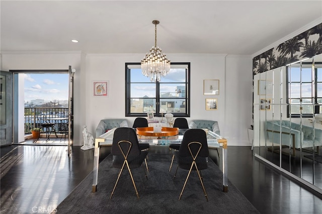 dining space with dark hardwood / wood-style flooring, crown molding, and a chandelier