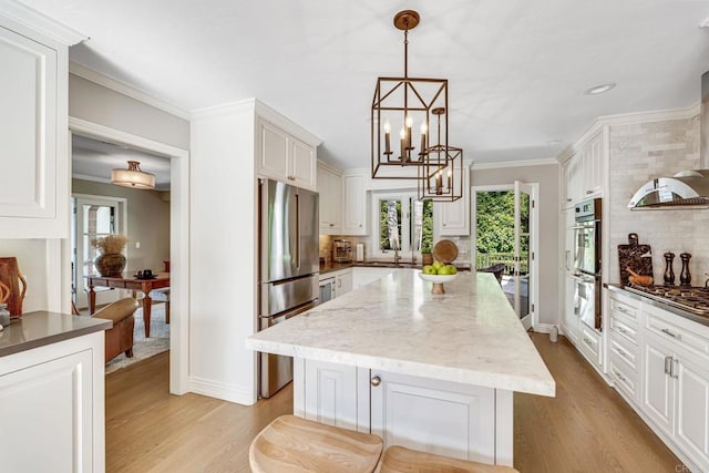 kitchen with a wealth of natural light, appliances with stainless steel finishes, and crown molding