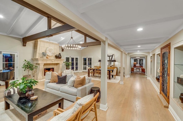 sunroom with a chandelier, a high end fireplace, vaulted ceiling with beams, and arched walkways